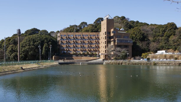 Un bâtiment à étages, doté d’une cour intérieure et bordé d’une étendue d’eau.