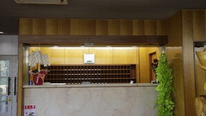 Un comptoir d’accueil avec un panneau décoratif en bois, une horloge et un extincteur.