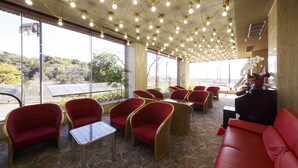 Un vaste espace intérieur doté de sièges rouges, de grandes fenêtres et d’un plafond orné de multiples luminaires.