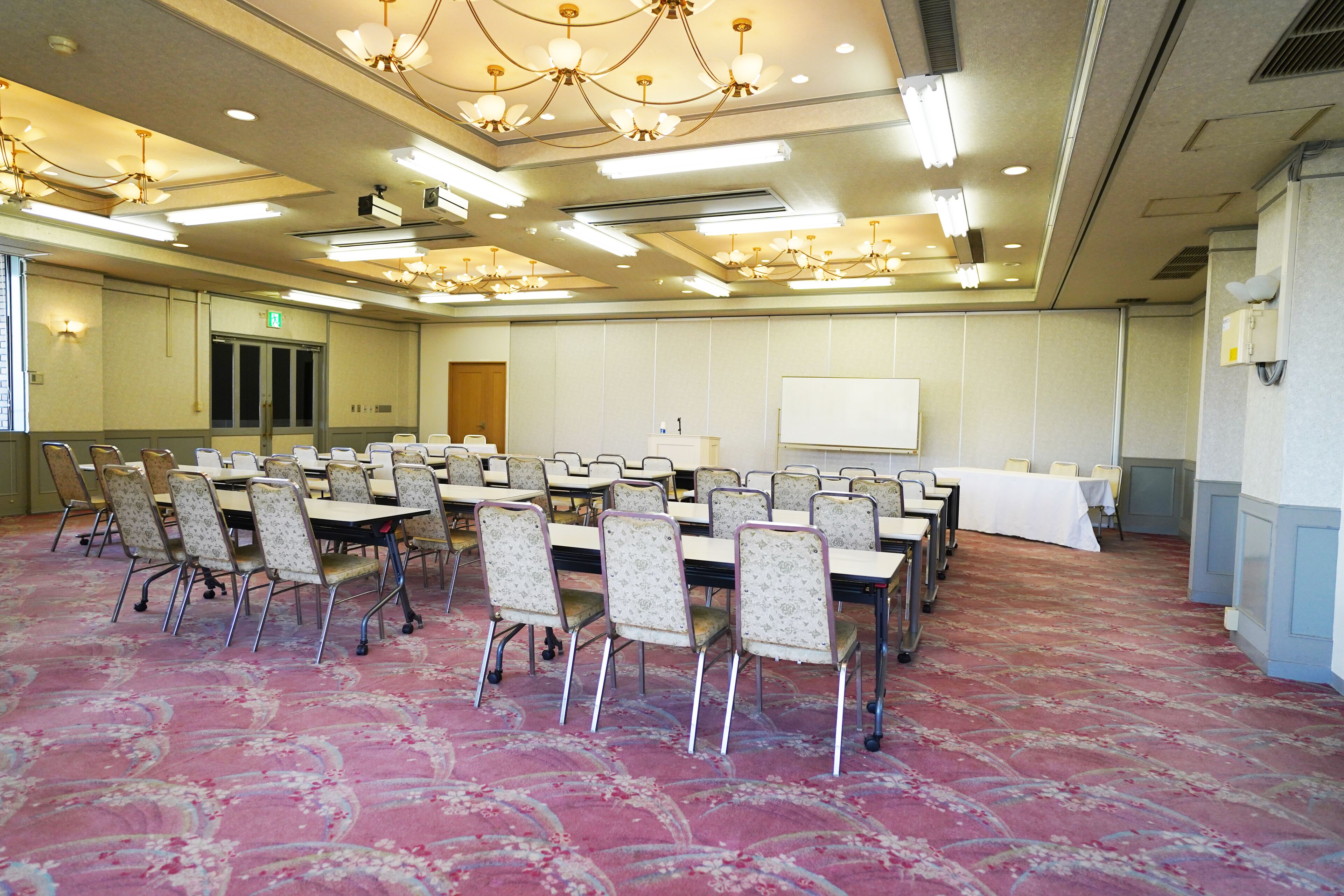 A conference room with rows of chairs, a whiteboard, and a carpeted floor.