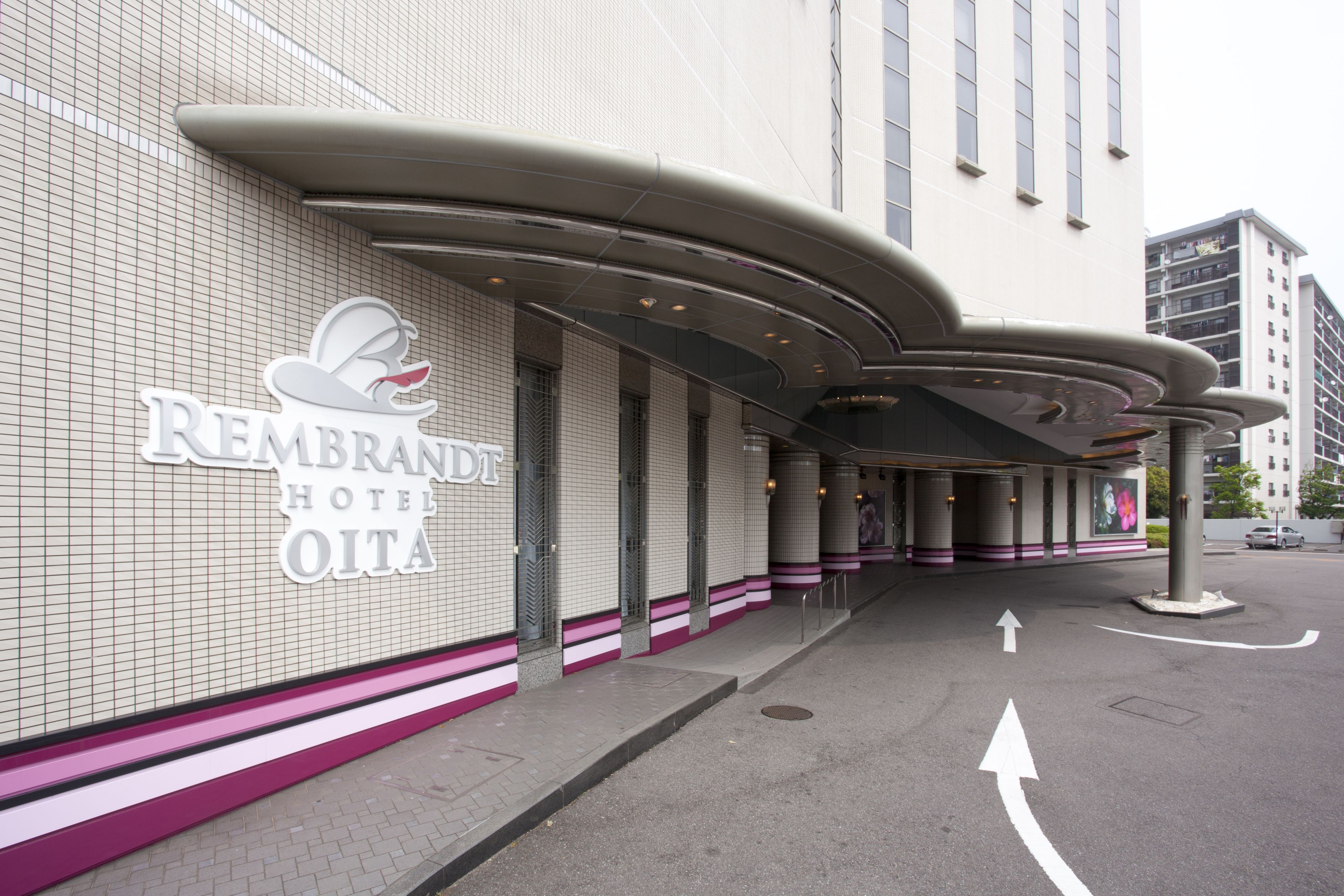 The exterior of Rembrandt Hotel Oita with a distinctive curved roof structure and a tiled facade.