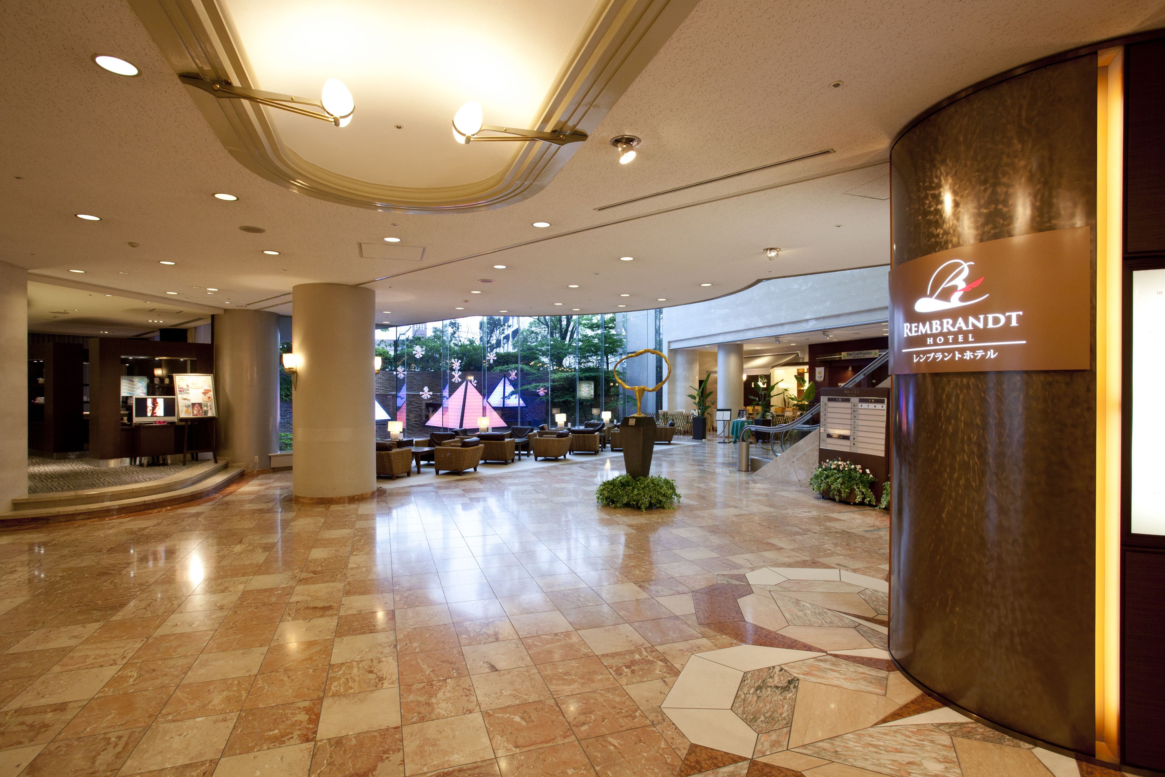 A spacious lobby with a checkered floor, seating areas, and a prominent hotel sign.