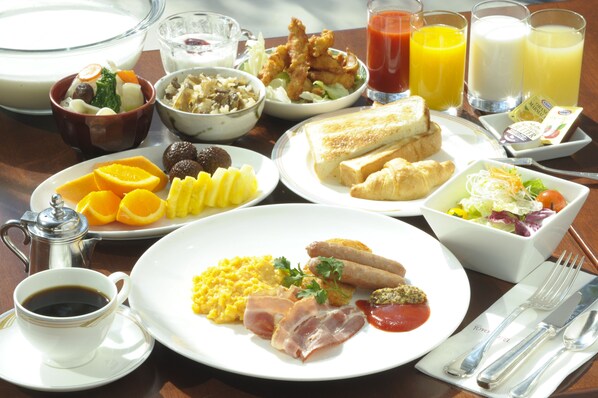 A breakfast table with various dishes including eggs, bacon, toast, and fruit.