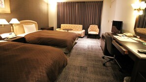 A hotel room with two beds, a desk, a chair, a small table, and a large mirror. - Rembrandt Hotel Oita (Oita)