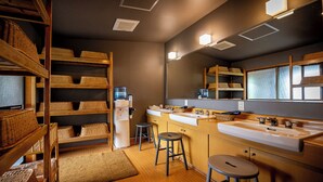 Une cuisine moderne avec des étagères en bois, un réfrigérateur, deux tabourets et un grand miroir au-dessus de l’évier.