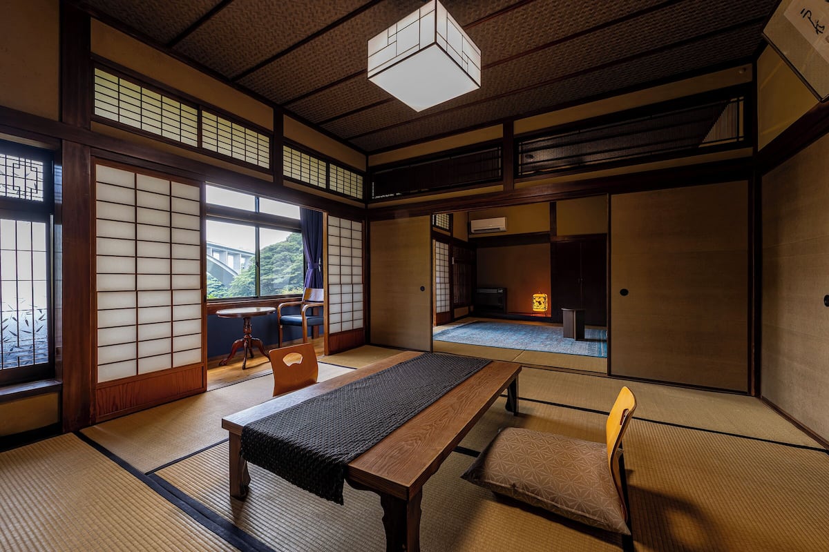 A traditional Japanese room with tatami flooring, a low table, and a sliding door.