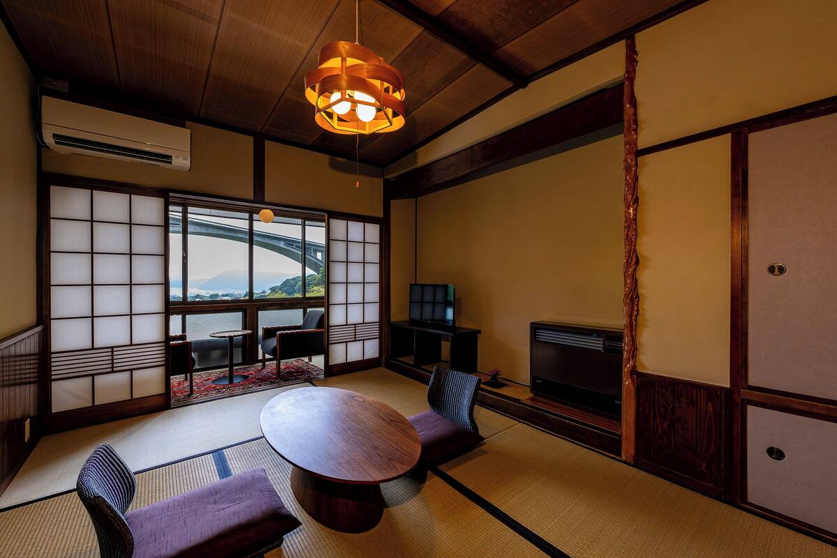 A traditional Japanese room with tatami flooring, a low table, and a television.