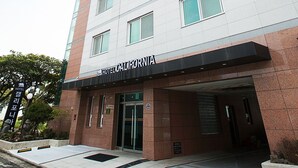 A modern hotel building with a prominent sign reading "HOTEL CALIFORNIA".