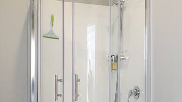 A modern bathroom with a glass-enclosed shower, a white toilet, and a wooden floor.