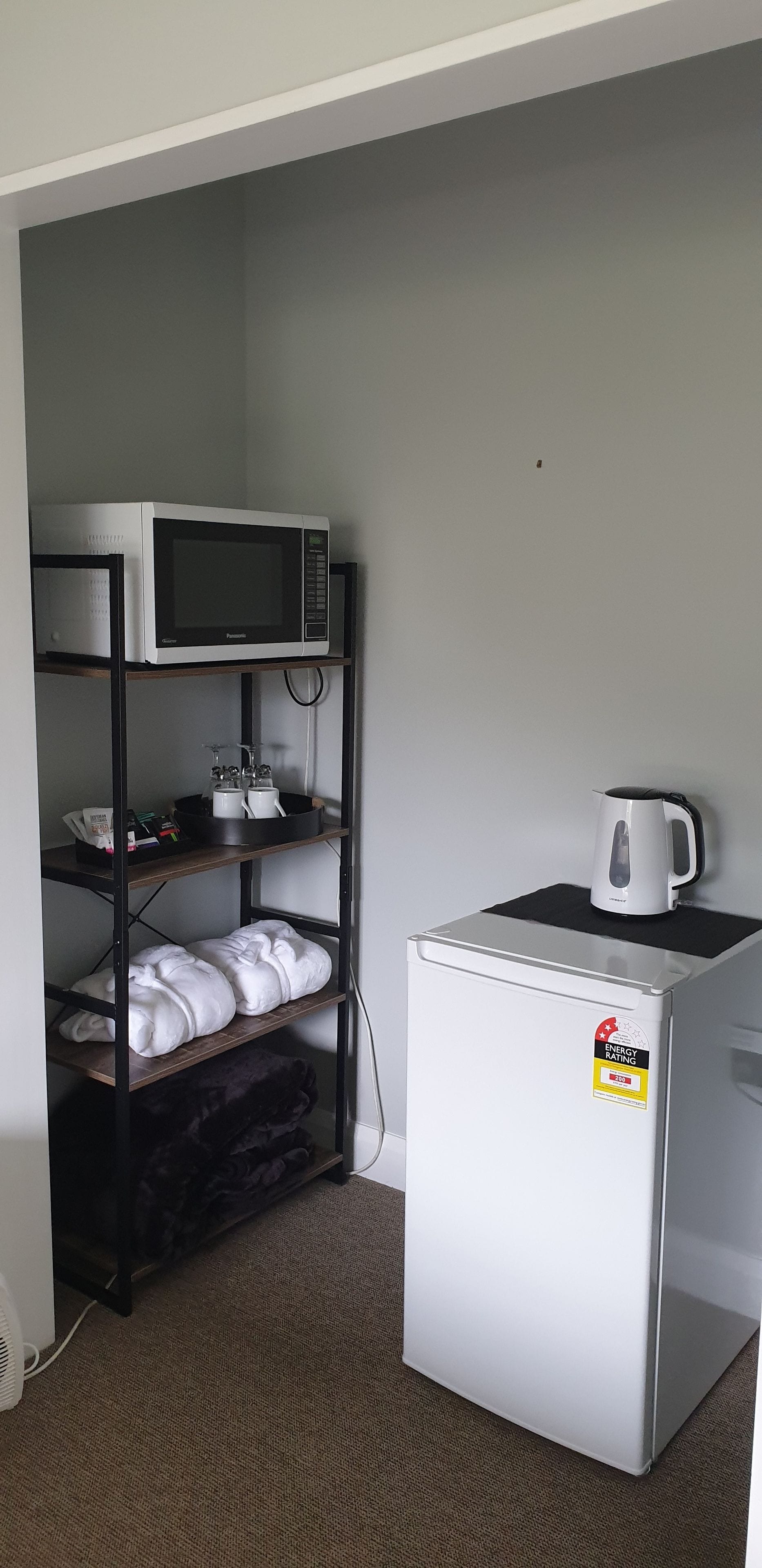 Una kitchenette compacta equipada con microondas, hervidor y refrigerador.