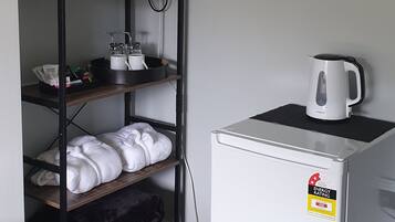 Una kitchenette compacta equipada con microondas, hervidor y refrigerador.