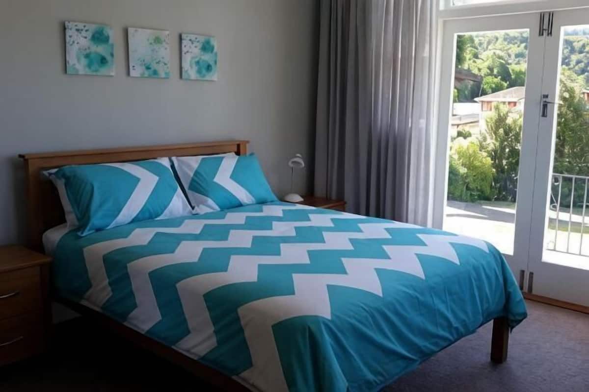 A bedroom with a bed, nightstands, and a view through a glass door.