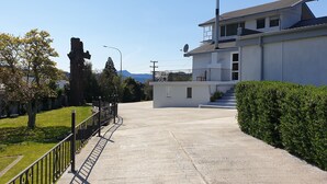 A residential street with a modern house, a concrete pathway, and a large tree. - Top of the Town (Picton)