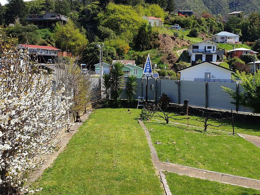 A residential area with a grassy lawn, a metal fence, and houses in the background.