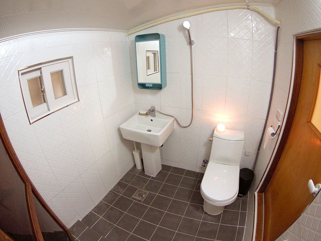 Un baño pequeño con inodoro, lavamanos y ducha.