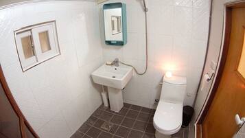 Un baño pequeño con inodoro, lavamanos y ducha.
