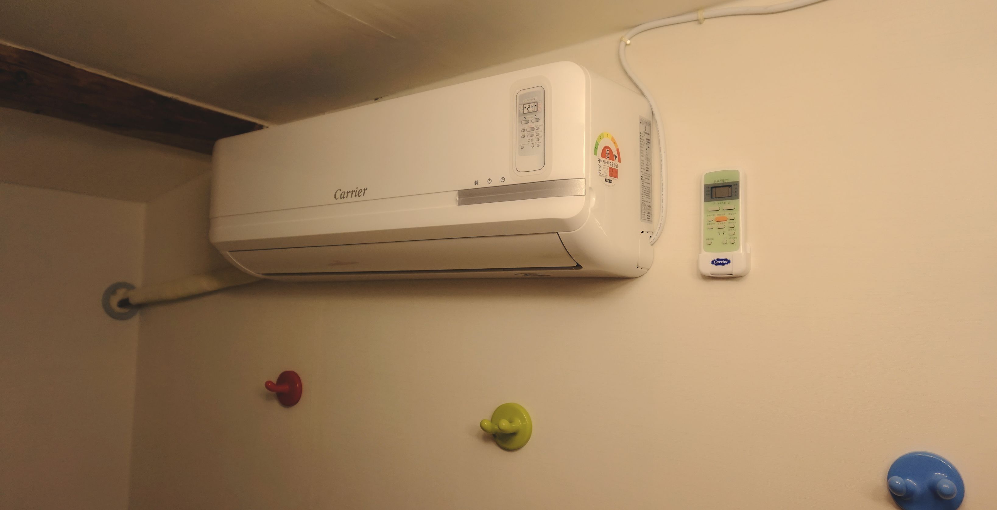 A wall-mounted air conditioner with a remote control and a wall-mounted thermostat.