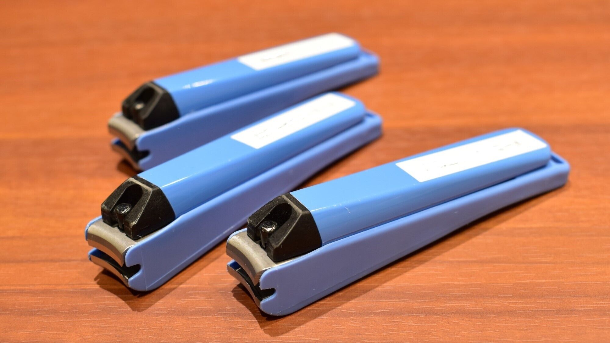 Trois objets bleus, chacun portant une étiquette, sont posés sur une surface en bois.