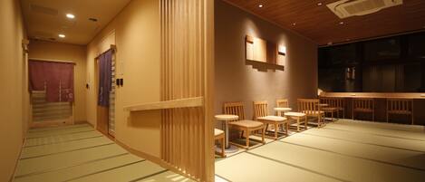 A traditional Japanese room with tatami flooring, wooden sliding doors, and a low ceiling with recessed lighting.