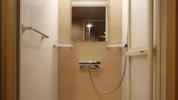 A narrow, enclosed bathroom with a shower, a mirror, and a toilet.