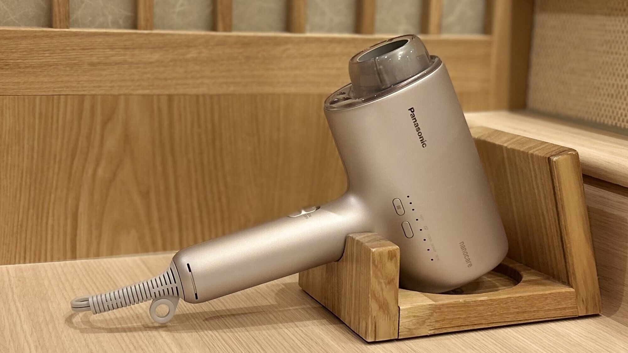 A portable hair dryer with a charging dock, placed on a wooden surface.