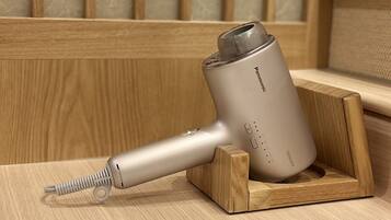 Un sèche-cheveux portable avec une station de recharge, posé sur une surface en bois.