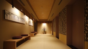 A hallway with a wooden bench, a vase with flowers, and a wall with a floral pattern. - Onyado Nono Nara Natural Hot Spring (Nara)