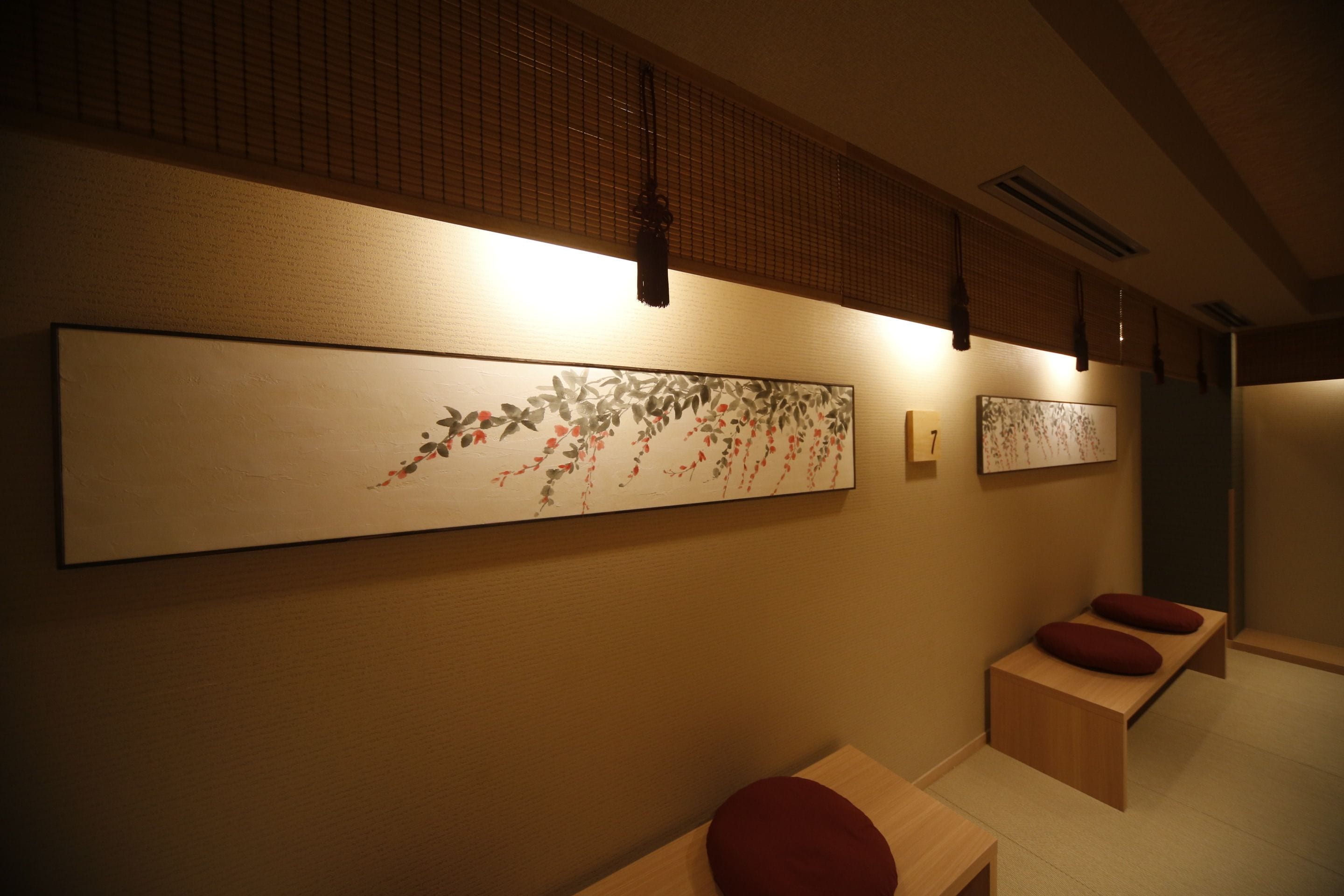 A spa room with a wooden bench, a wall-mounted massage table, and a large abstract painting.