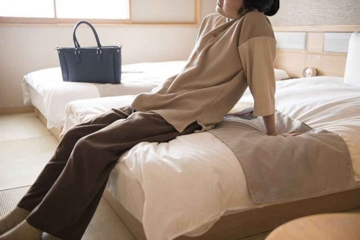 A room with a bed, a blue bag, and a window.