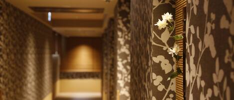 A corridor with patterned walls and a floral decoration on the right.