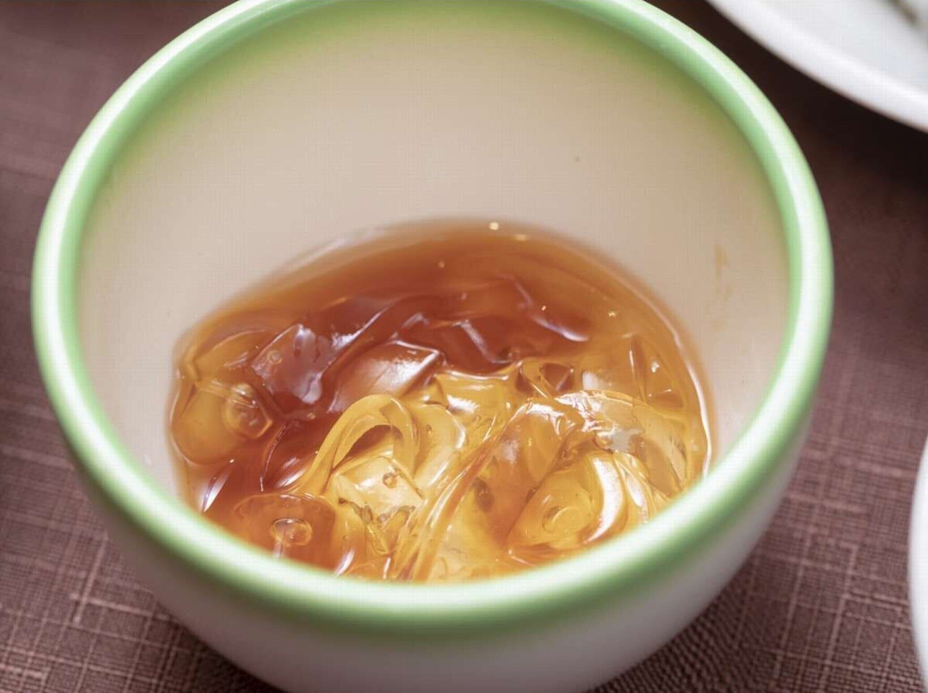 A bowl of tea with ice cubes.