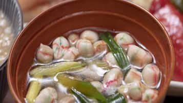 A bowl of soup with round dumplings and green vegetables.