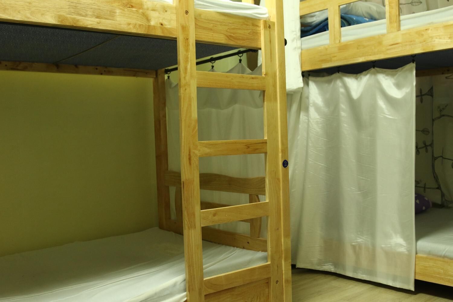 A bunk bed room with a wooden ladder, a curtain, and a mattress.