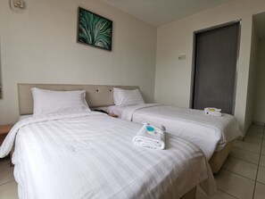 Une chambre d’hôtel avec deux lits, du linge de lit blanc, un tableau au mur et une porte sur le côté droit.