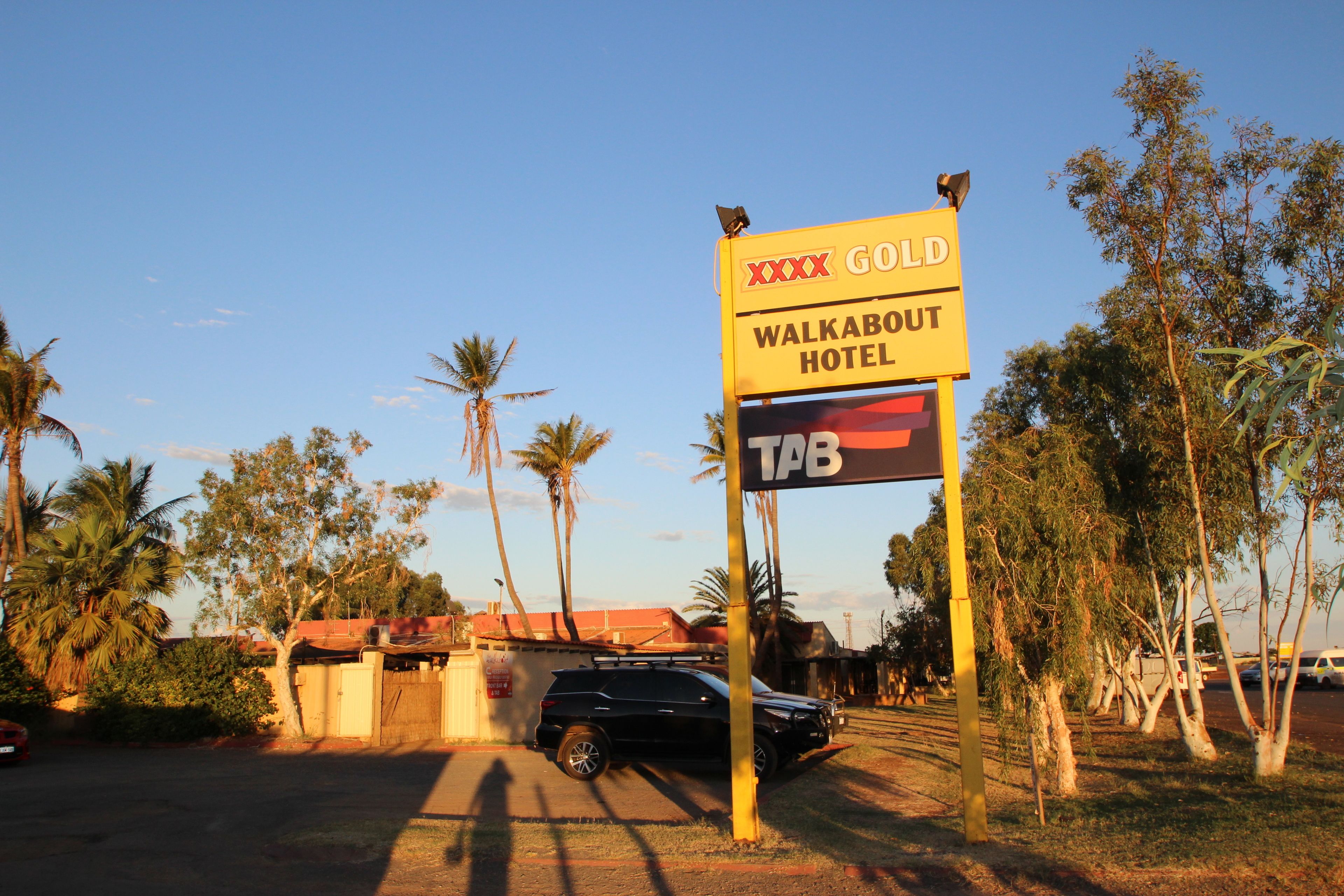 Une enseigne pour l’hôtel Walkabout, avec un emblème doré, le logo TTB et une caméra de surveillance.