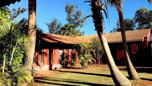 Un patio con un edificio de techo rojo, palmeras y un césped bien cuidado.