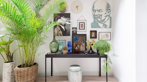 A room with a black console table displaying various artworks, a large green plant, and a vintage fan.