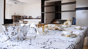 A dining area with a table set for tea, featuring white and gold teacups and saucers, and a lace tablecloth. - LA DOLCE VITA ON LAKE ISEO (Lovere)