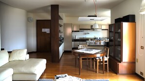 A modern living room with a sofa, a dining table with chairs, and a kitchen area with cabinets and appliances. - LA DOLCE VITA ON LAKE ISEO (Lovere)