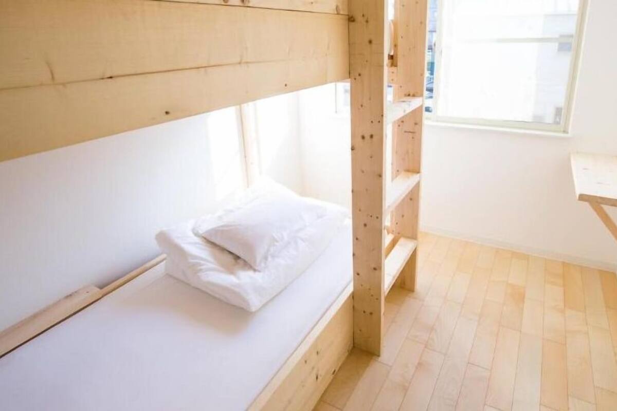 Ein kleines Zimmer mit einem Einzelbett, einem Holzbettkasten und einem kleinen Schreibtisch.