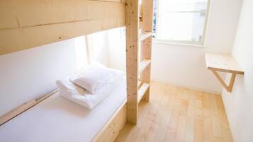 A small, single-bed room with a wooden bunk bed and a small desk.
