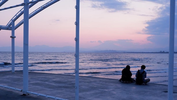 Un paseo marítimo con barandillas de metal y vista al mar al atardecer.