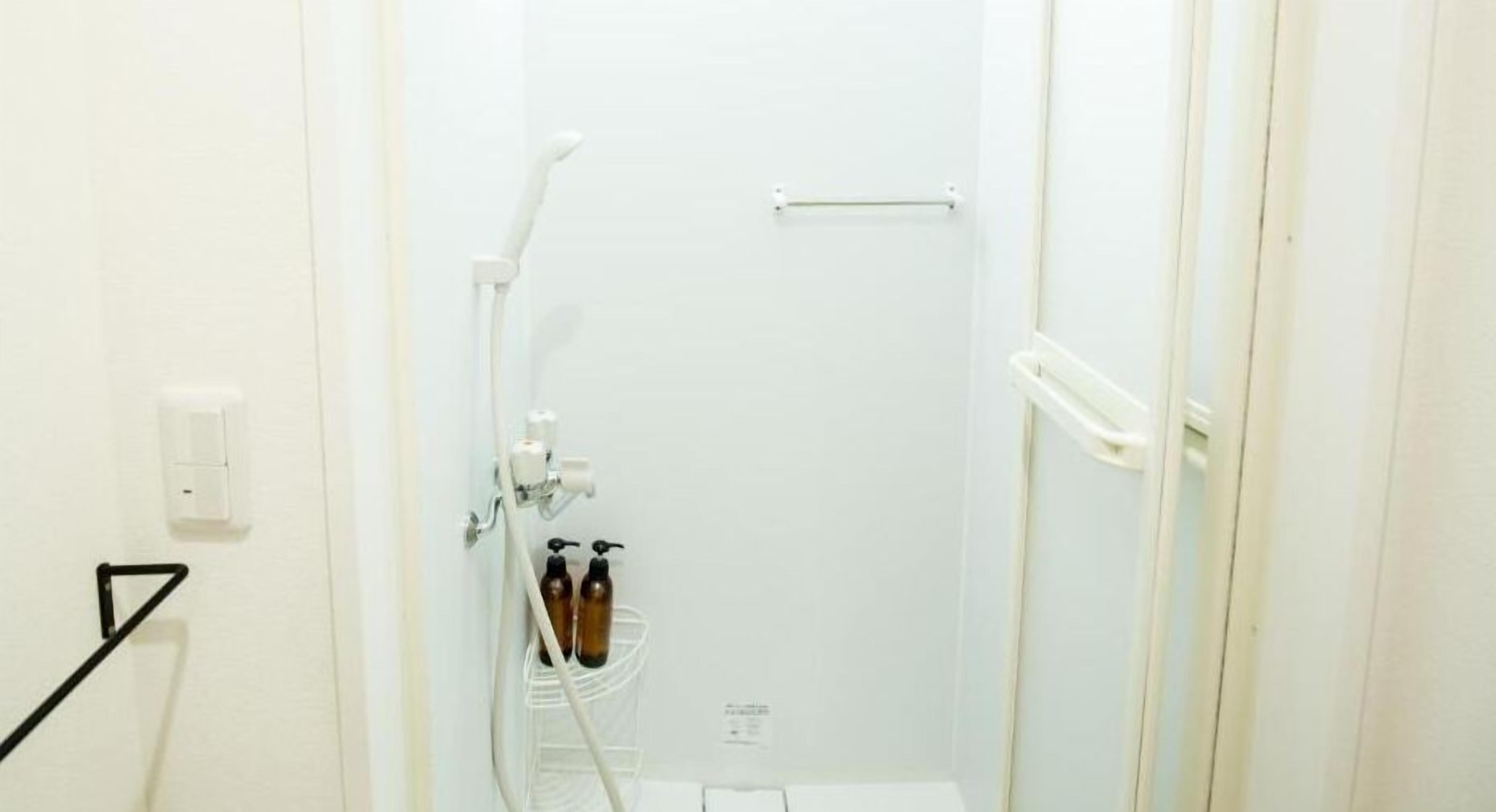 Een badkamer met een douche, een handdoekrek en een fleshouder.