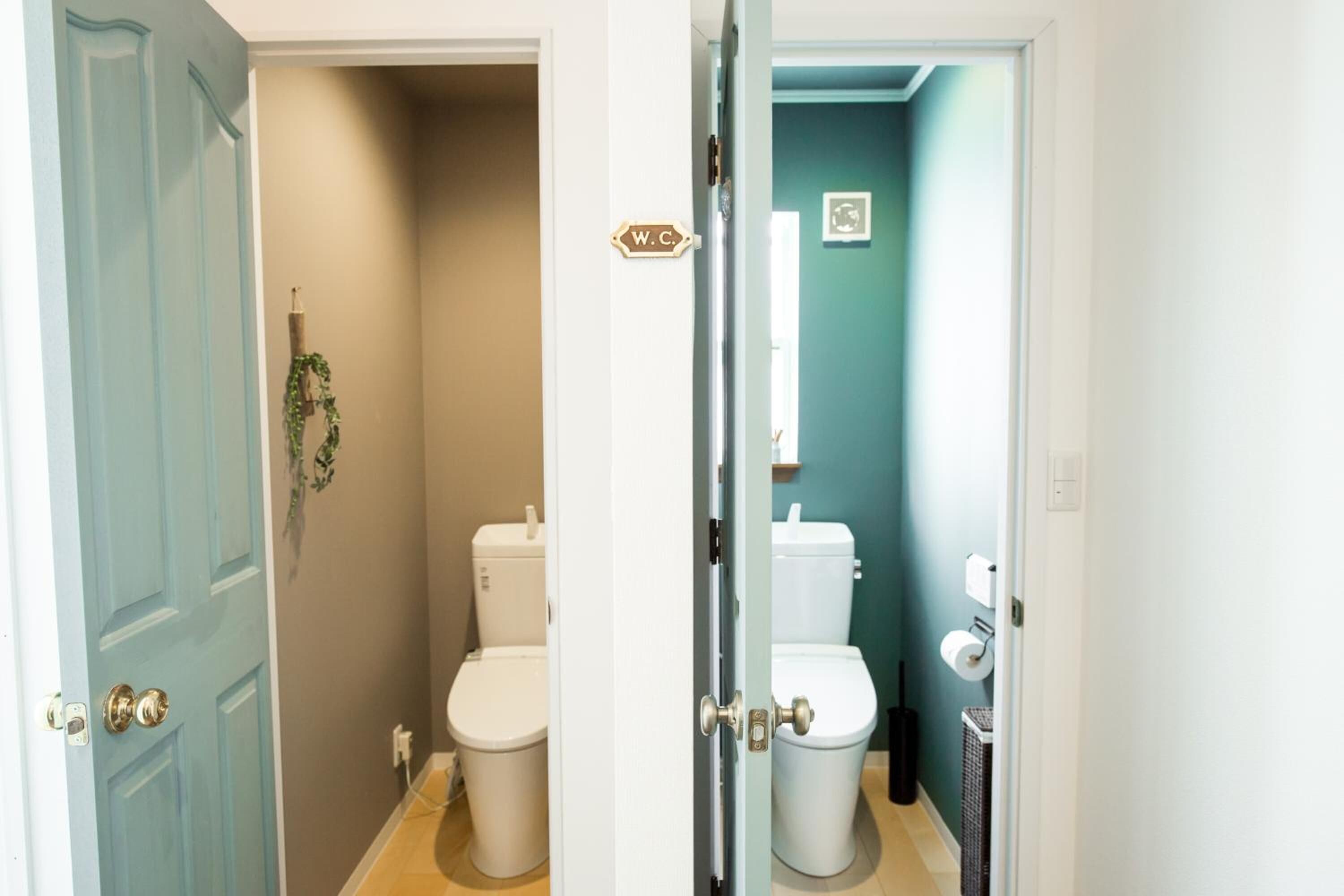 Une salle de bain avec deux toilettes, un panneau indiquant les toilettes et un porte-serviettes.