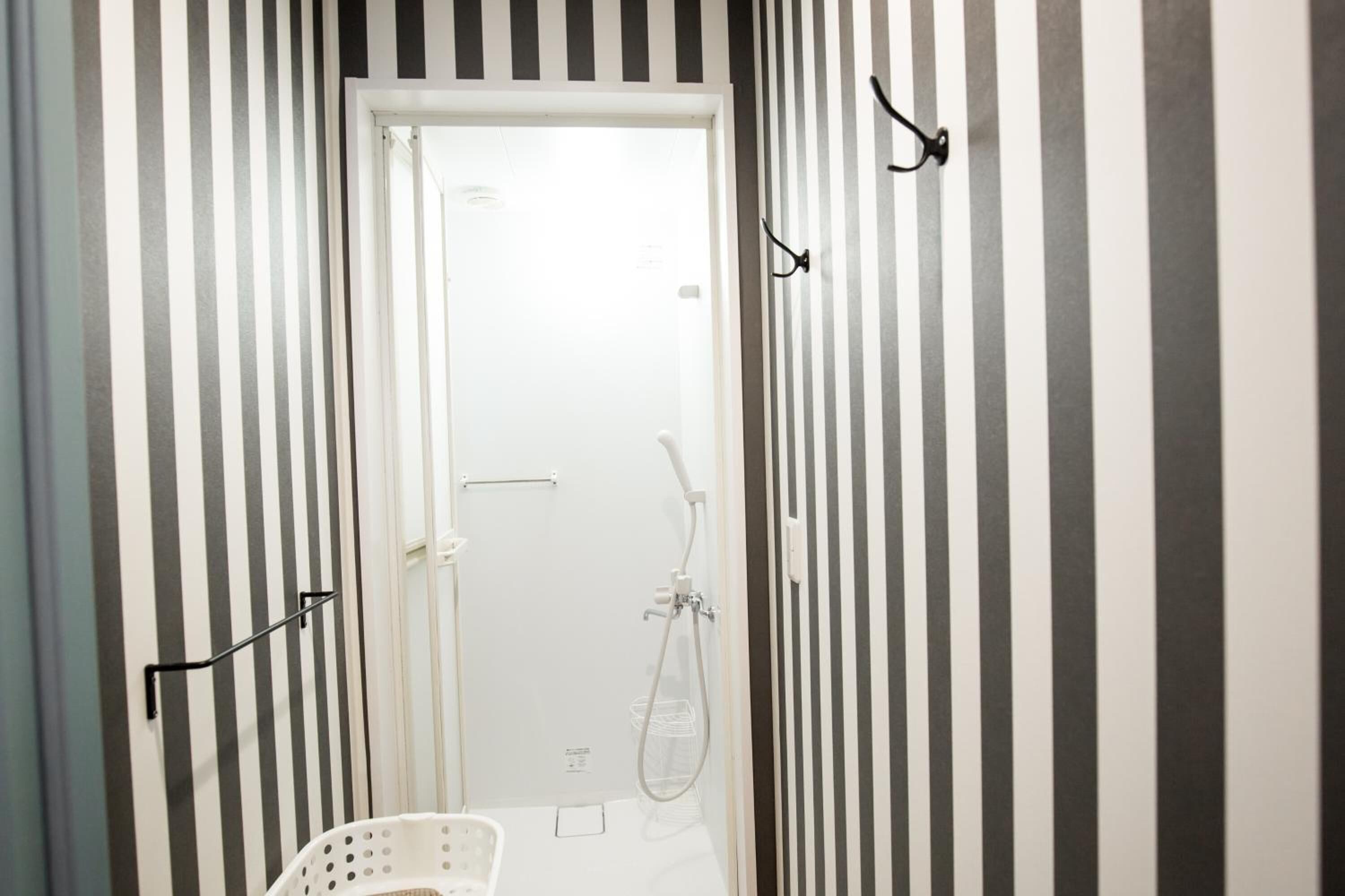 Un baño con paredes a rayas, una ducha y una puerta blanca.
