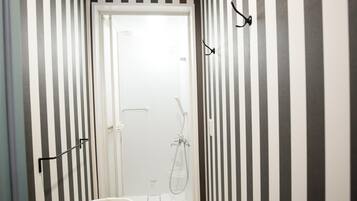 Un baño con paredes a rayas, una ducha y una puerta blanca.