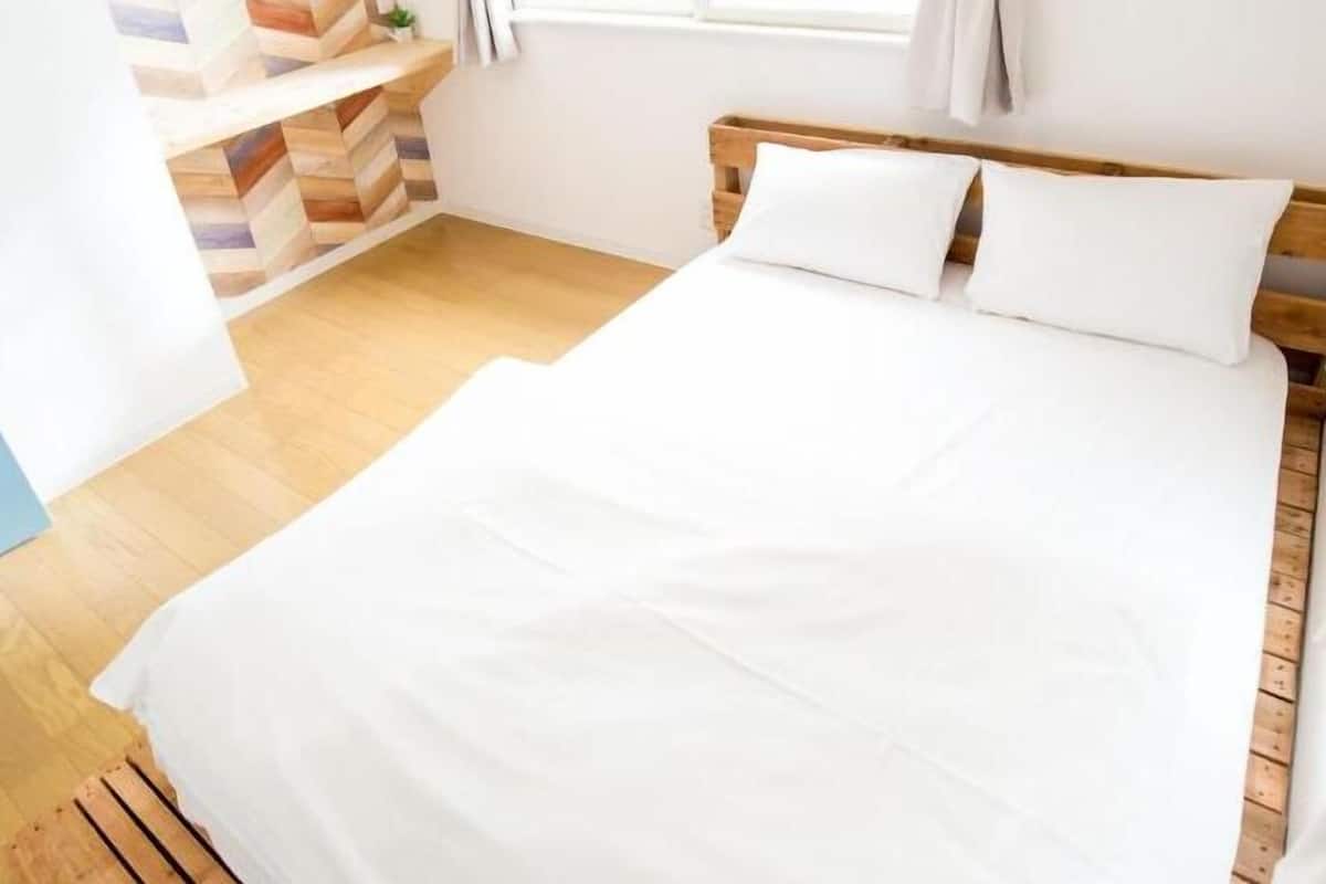 Ein Schlafzimmer mit einem hölzernen Bett, weißer Bettwäsche und einer Wand mit Zickzackmuster.