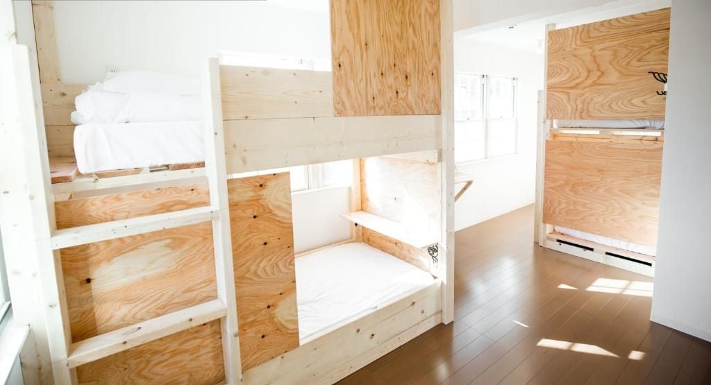 A dormitory room with bunk beds, wooden walls, and a window.
