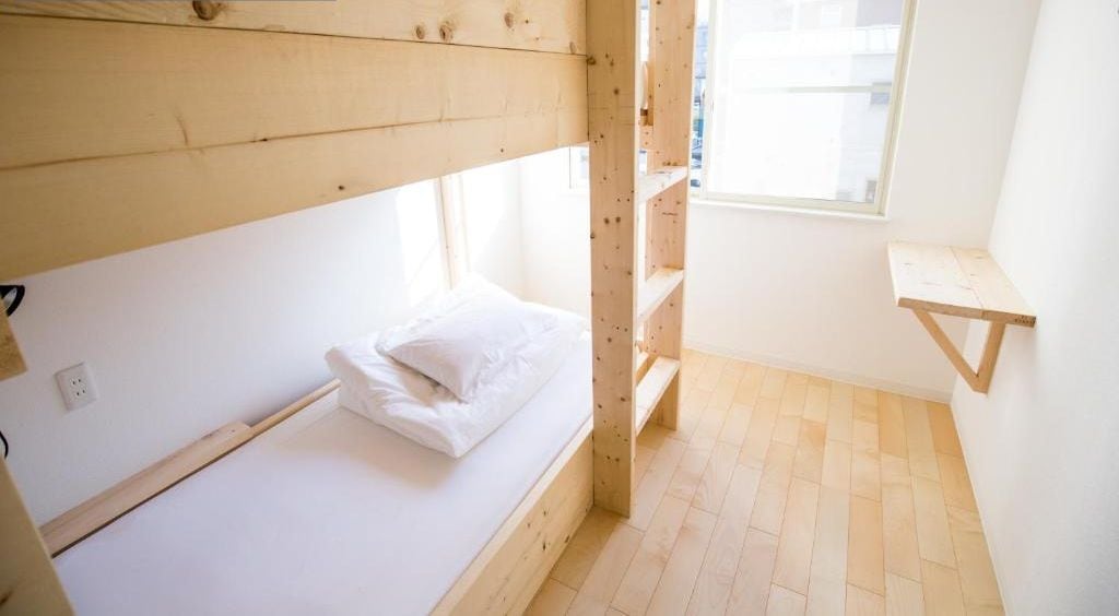 Ett privat dubbelrum med en våningssäng, ett litet fönster och en hylla i trä.