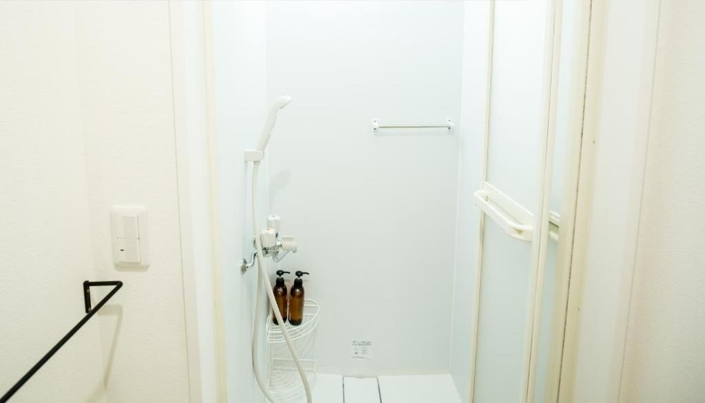 Une salle de bain avec une douche, un porte-serviettes et deux bouteilles de shampoing et d’après-shampoing.